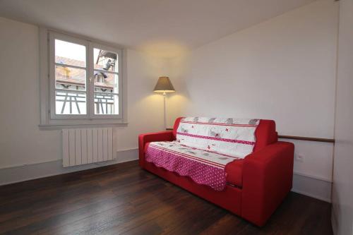 利克维Chambre chez l'habitant Le Rouge-Gorge - Cœur de Riquewihr - 2 personnes的窗户房间里一张红色的沙发