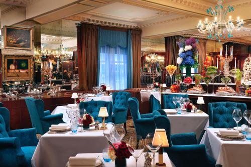 伦敦红色康乃馨皇宫中的鲁本斯酒店的餐厅设有白色的桌子和蓝色的椅子