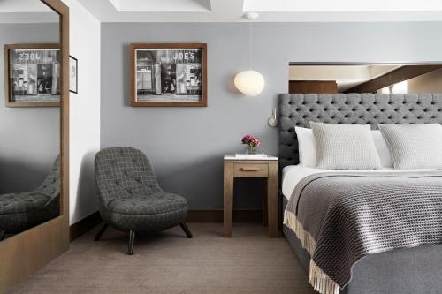 格拉斯哥Kimpton - Blythswood Square Hotel, an IHG Hotel的一间卧室配有一张床、一把椅子和镜子