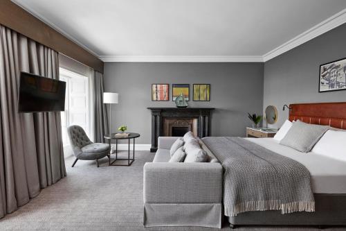 格拉斯哥Kimpton - Blythswood Square Hotel, an IHG Hotel的一间卧室配有一张床、一张沙发和一个壁炉