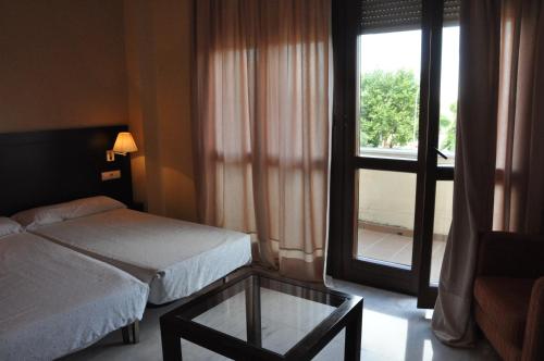 塞维利亚卢克瑟维亚宫公寓的一间卧室设有一张床、一张玻璃桌和一扇窗户