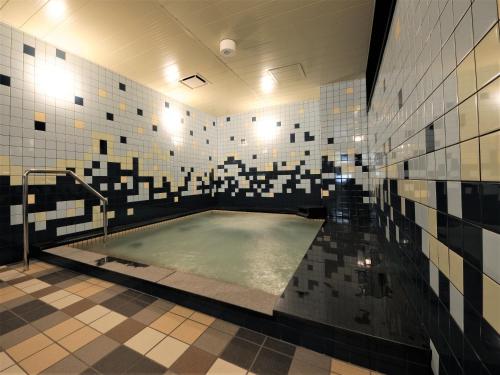 鸟取市Green Rich Hotel Tottori Ekimae (Artificial hot spring Futamata Yunohana)的黑色和白色瓷砖浴室内的大型游泳池
