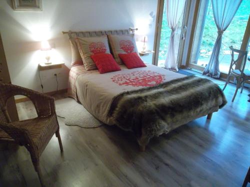 Le NoyerLa Buissonnière的一间卧室配有一张带红色枕头的大床