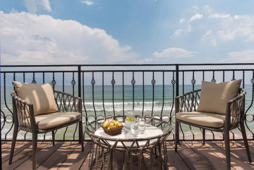 克兰内沃Effect Algara Beach Resort - Ultra All Inclusive and Free Parking的阳台配有两把椅子和一张带一碗水果的桌子。