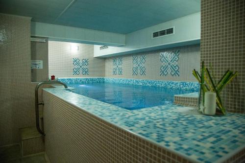萨帕雷瓦巴尼亚Family Hotel Emaly Green的蓝色瓷砖浴室内的大型游泳池