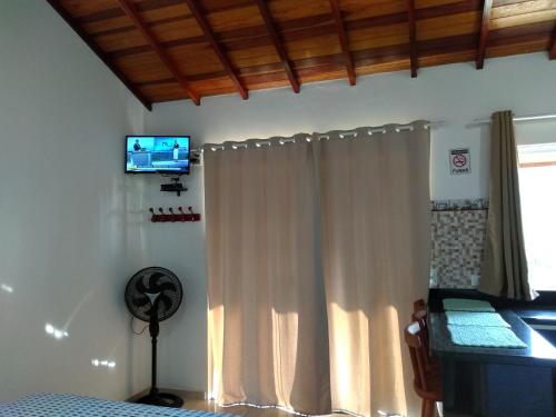 帕拉蒂Chalés Vale dos Pássaros的卧室配有白色窗帘和墙上的电视