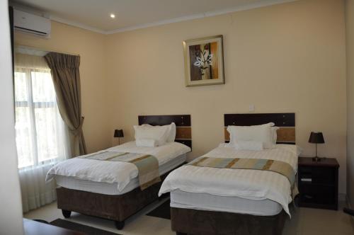 哈博罗内Bannerloft Guest house的酒店客房设有两张床和窗户。