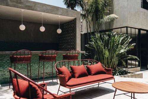 瓜达拉哈拉Casa Ixaya by Barrio México的庭院配有红色的椅子、桌子和桌椅