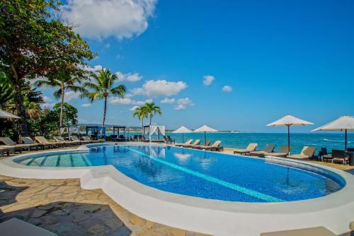 喀巴里特维林罗海滩公寓式度假酒店的毗邻大海的游泳池,配有椅子和遮阳伞