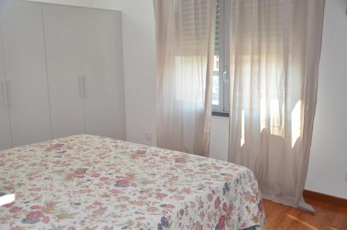 比萨Tuttomondo的一间卧室配有一张带花卉床罩的床和窗户。