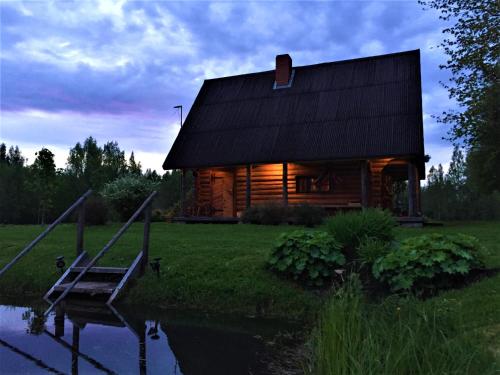 SīveciPirts Baudas的小木屋前面设有池塘