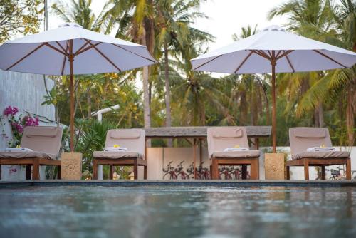 吉利特拉旺安Villa Luna Sunset Beach的一组椅子和遮阳伞,位于游泳池旁