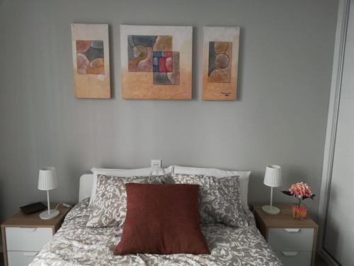 萨拉戈萨Cesar Augusto House的卧室,在床上方墙上装饰有三幅画