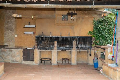 索尔索纳Casa rural Sant Grau turismo saludable y responsable的一个带两把椅子的庭院和墙上的烧烤架