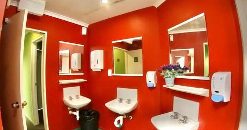 罗托鲁瓦罗托鲁瓦市中心背包客旅舍的红色的浴室设有两个盥洗盆和镜子