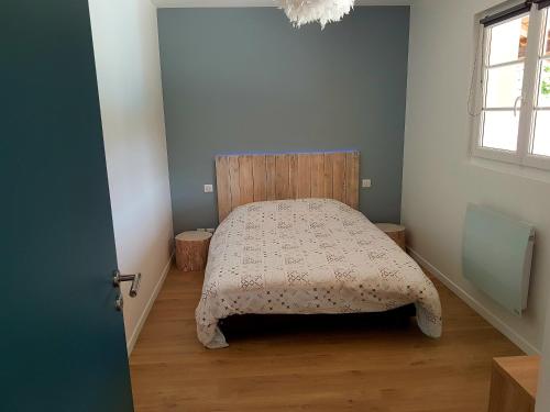 Moulainville-la-BasseDépendance au goût de vacances的一间卧室配有一张带木制床头板的床和窗户。