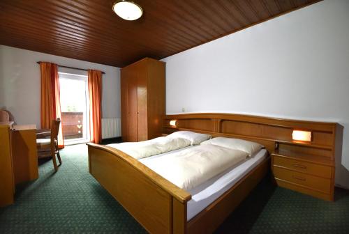 魏勒格Hotel&Wirtshaus Sonne的一间卧室配有一张带木制床头板的床和窗户。