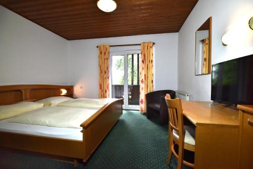 魏勒格Hotel&Wirtshaus Sonne的一间卧室配有一张床、一张书桌和一台电视