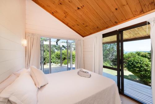 SurfdaleWaiheke Island Vineyard Holiday Houses的一间卧室设有一张床和一个大窗户