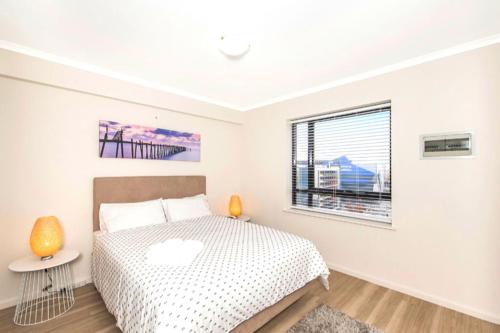 珀斯Perth West End Apartment 601的白色的卧室设有床和窗户