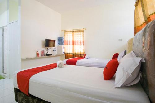 先达RedDoorz @ Pematangsiantar 2的客房内的两张床和红色枕头