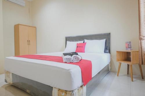占碑市RedDoorz Syariah near Kantor Walikota Jambi的卧室配有一张大白色床和红色毯子