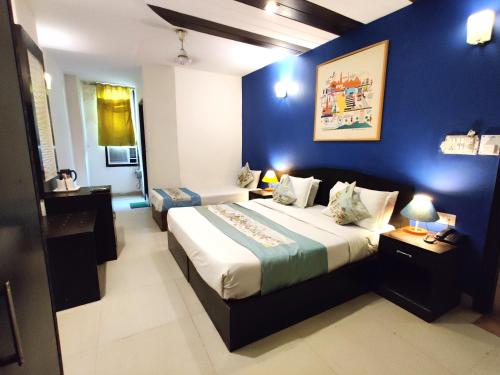 新德里Hotel Unistar的一间卧室设有一张蓝色墙壁的大床