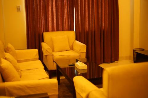 吉大港THE AVENUE HOTEL & SUITES的客厅配有椅子、椅子和桌子