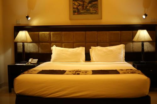 吉大港THE AVENUE HOTEL & SUITES的酒店客房设有一张大床和两盏灯