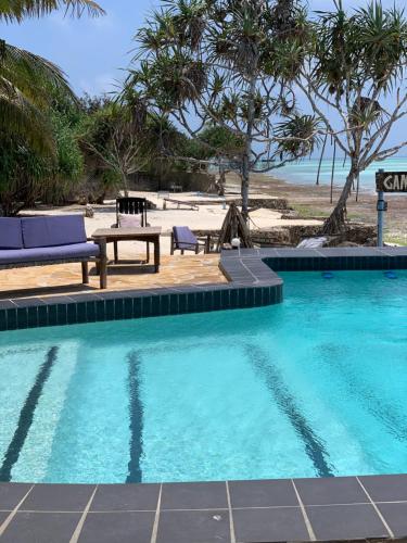 南威游戏鱼旅馆的海滩旁的游泳池配有桌椅