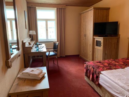 施托尔彭Hotel Goldner Löwe的酒店客房配有一张床、一张书桌和一台电视。