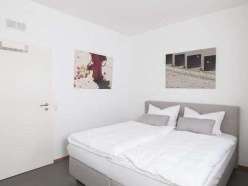 蒂宾根Gästewohnung Jakobsgasse的卧室内的一张白色床,墙上挂着两张照片