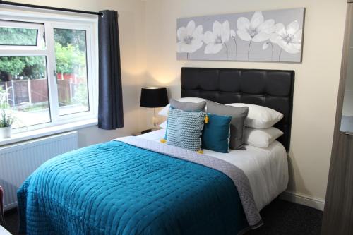 伍尔弗汉普顿霍尔康柏公寓式酒店的一间卧室配有一张带蓝色毯子的床和窗户。