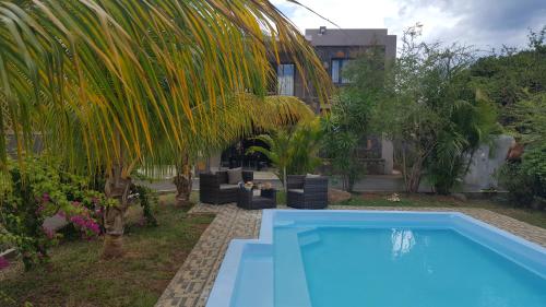 弗利康弗拉克Aux plaisirs de la vie的棕榈树屋前的游泳池