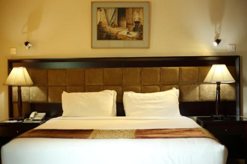 吉大港THE AVENUE HOTEL & SUITES的一间卧室配有一张大床、两盏灯和一部电话