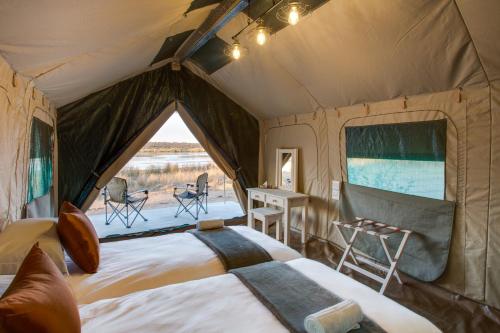 KlipdriftLittle Mongena Tented Camp的帐篷配有一张床和一张桌子及椅子