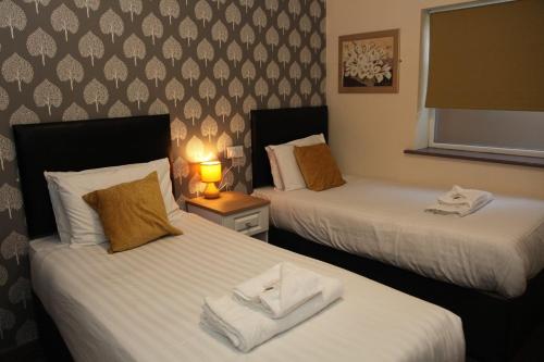 Minworth明维斯酒店的两张位于酒店客房的床,配有毛巾
