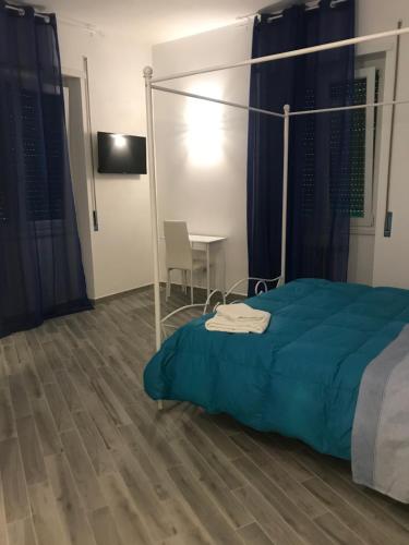 罗马LunaBlù Cinecitta'的一间卧室配有一张带蓝色毯子和一张桌子的床。