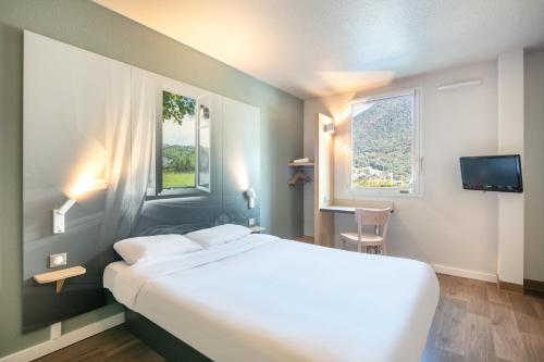 Sainte-Marie-de-CuinesB&B HOTEL Saint Jean De Maurienne的一间设有大床和窗户的酒店客房