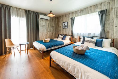 宜野湾市ペンション マカナレアビーチ沖縄的一间卧室配有两张床和一张桌子及椅子