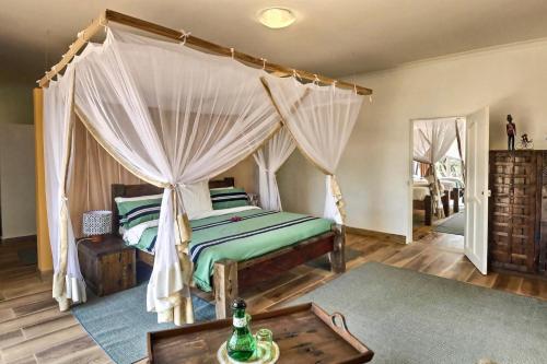 阿鲁沙Olerai Lodge的一间卧室配有一张天蓬床和一张桌子