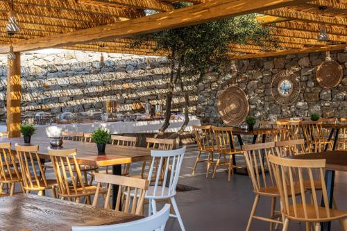 普拉迪斯亚罗斯Mykonos Drops的一间设有木桌和椅子的餐厅以及石墙