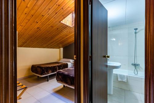 阿林萨尔Apartamentos Turisticos Poblado的一间带两张床、浴缸和水槽的浴室