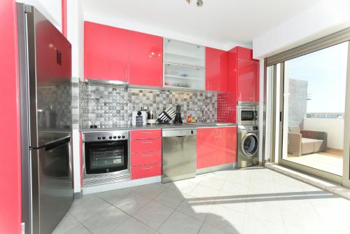 波尔蒂芒Exclusive Luxury Apartments in Oceano Atlantico Complex的红色的厨房,配有不锈钢用具和红色橱柜
