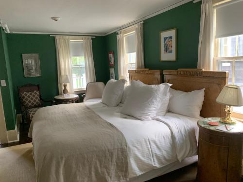 布里奇汉普顿Bridgehampton Inn的一间卧室设有绿色的墙壁和一张带白色枕头的床。