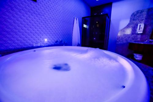 布卢梅瑙Amy Motel的浴室设有白色浴缸,享有蓝色的灯光