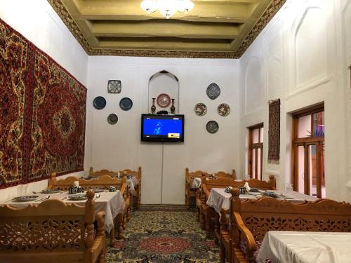 布哈拉Old Bukhara Boutique的一间设有桌子的用餐室和墙上的电视