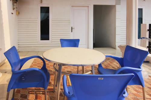 LampungOYO 1456 Hotel Garuda的一张带蓝色椅子的桌子和一张白色桌子