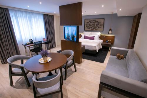 马尼拉Coro Hotel的酒店客房设有沙发、桌子和床。
