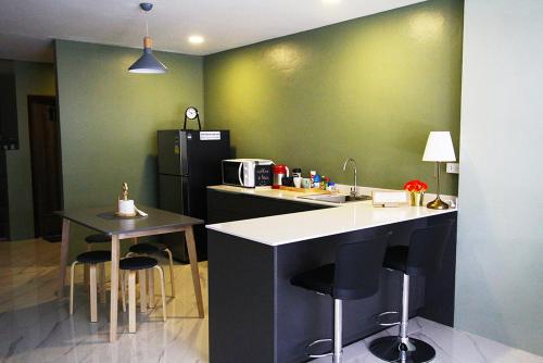 曼谷398 HOSTEL的厨房设有绿色的墙壁和带凳子的台面